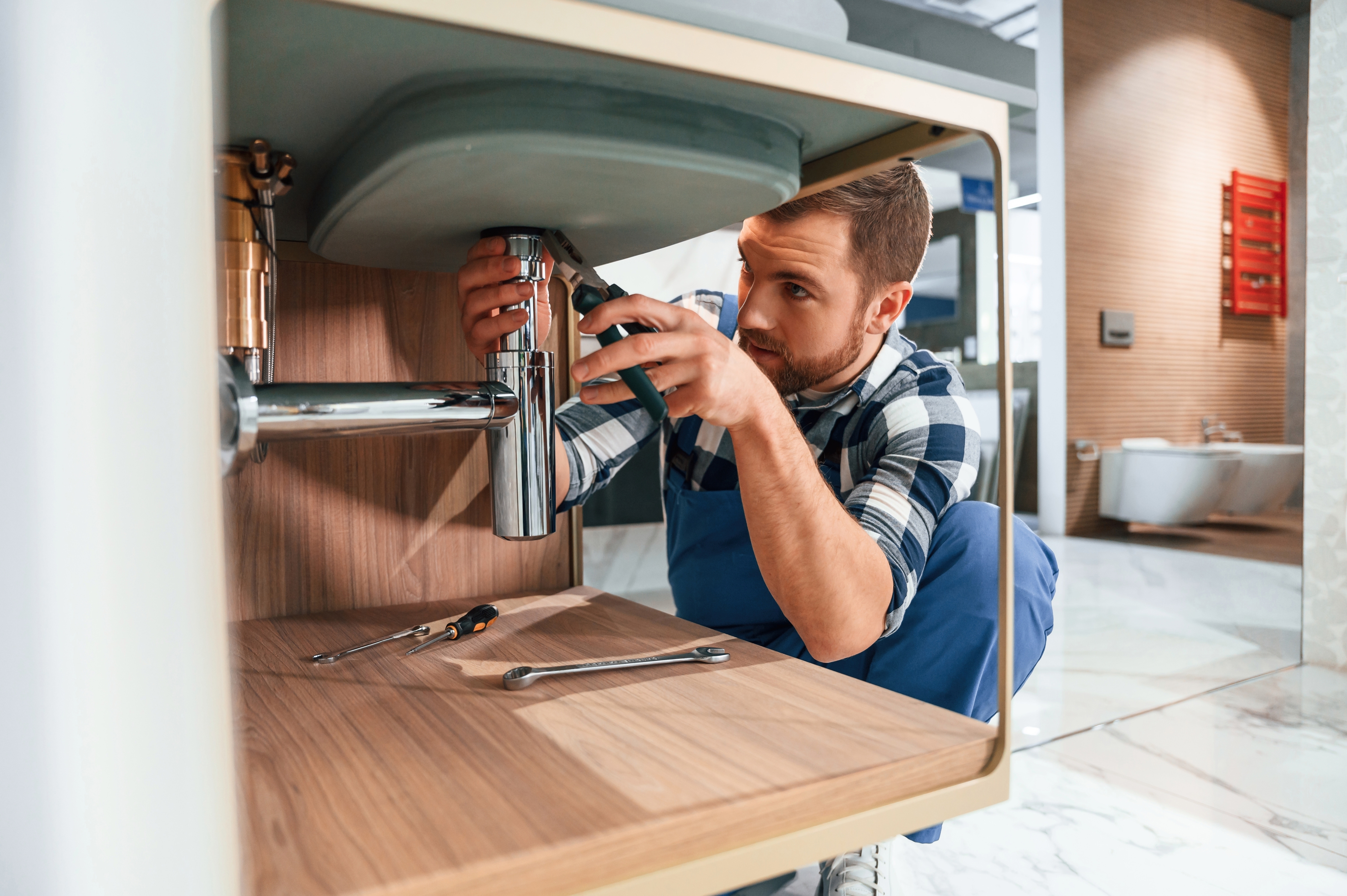 Drain King technician fitting a chrome trap under a sink