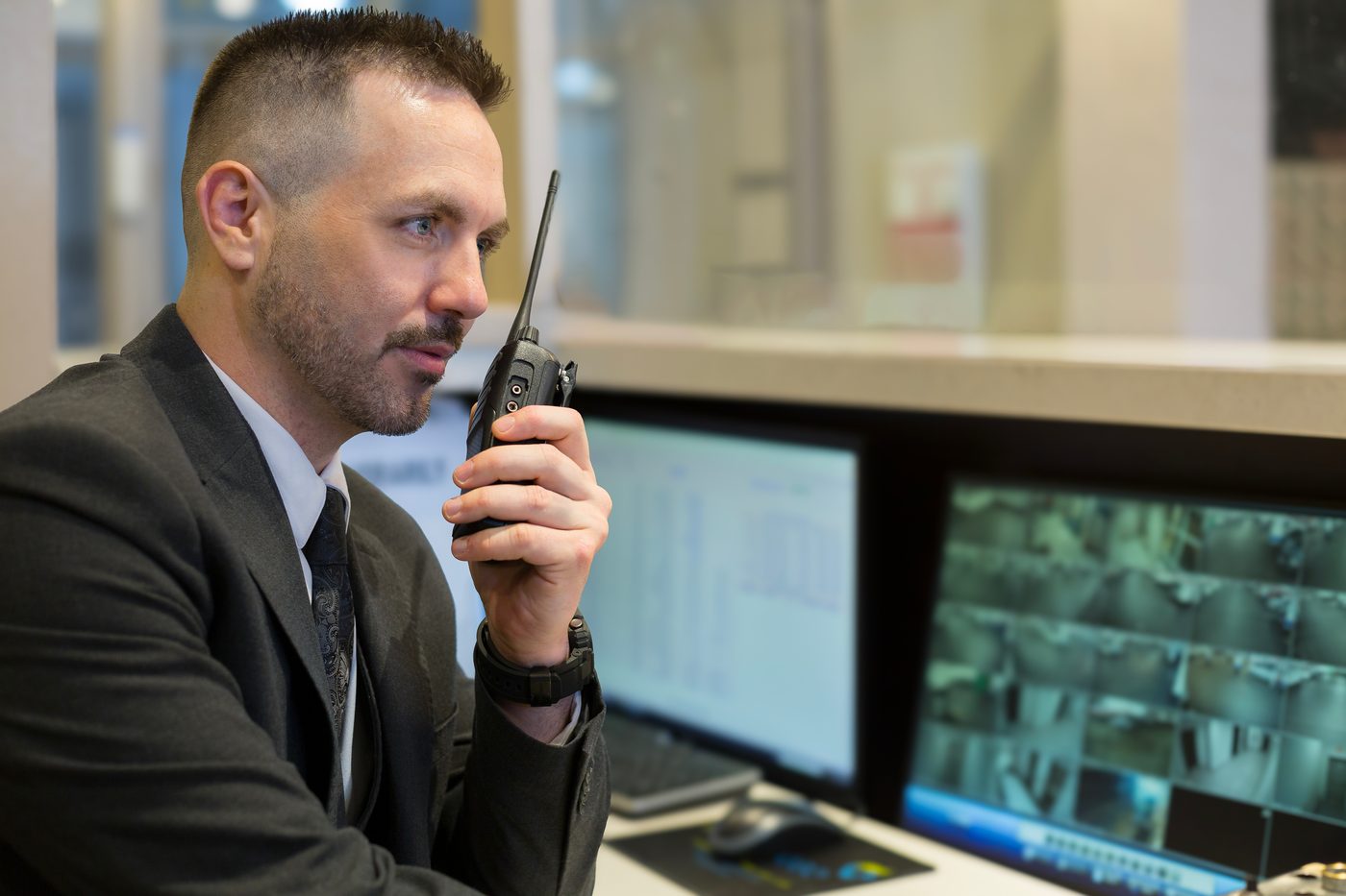 A Probe security guard coordinating on radio at a condominium monitoring console