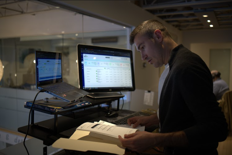 A TechWyse specialist reviewing client performance reports at a standing desk